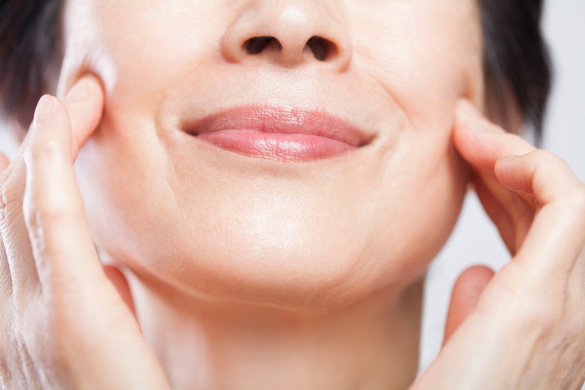 woman smiling while touching her supple face cheeks