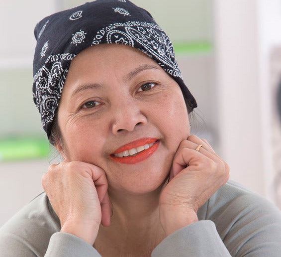 smiling middle-aged woman with bandana over her balding head from chemo