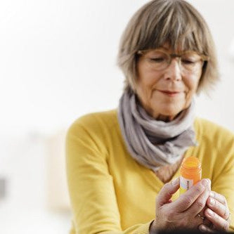 elderly woman looking concerned reading the label on her medicine bottle